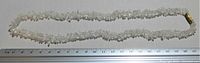 Full length image of the quartz crystal chip necklace next to a ruler showing the length.