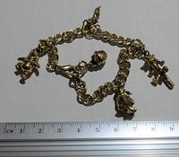 Full view of gold-tone link charm bracelet with multiple character charms including Winnie the Pooh, approximately 7 to 8 inches long measured with ruler