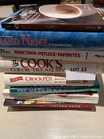 Stack of 8 cookbooks showing titles and book types, including coffee recipe book on top and Stefano Faita book on bottom.