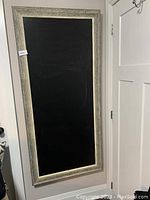 Single large framed blackboard leaning against a wall, showing size and frame detail