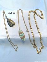 Overview of three necklaces including stone pendant, enamel filigree pendant, and geometric link chain