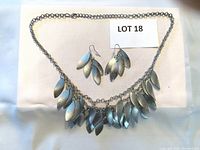 Necklace and earrings laid out showing leaf-shaped dangle design on silver-tone chain and hooks.