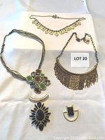 Three necklaces and two pendants arranged on white background showing design details.