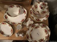 Full set of Royal Albert Old Country Rose bone china dishes arranged on table, showing stacked plates and bowls with floral patterns and gold trim.