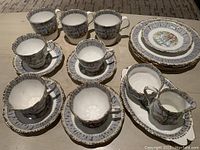 Full set displayed showing coffee mugs, teacups, saucers, dessert plates, creamer, and sugar bowl on platter with Silver Birch design and gold accents.