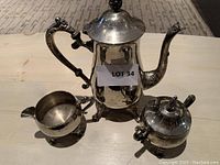 Photo showing the full tea set with teapot, creamer, and sugar bowl on a wooden surface.