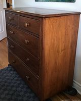 Full side and front angled view of the dresser showing wood grain and knobs.