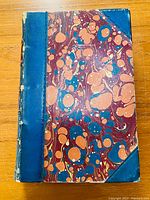 Front cover of The Bastonnais book showing marbled pattern with blue leather spine and corners, some wear on edges.