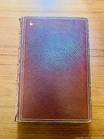 Top view of front cover showing brown leather with gold border and some edge wear especially on the left side along spine.
