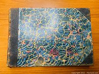 Front cover of the book showing marbled pattern with leather spine and corners.