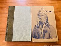 Hardcover book with suede-like spine and canvas cloth cover alongside illustrated folio slipcase depicting a Native American man.