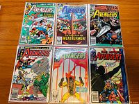 Top-down photo of six Avengers comic books laid out in two rows showing full covers with superhero artwork and titles.