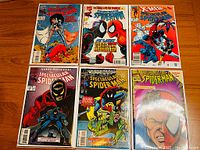 Full lot overview showing six different issues of The Spectacular Spider-Man comics laid out on a wooden surface showcasing their brightly colored covers featuring Spider-Man, X-Men, and other characters.