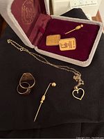Overview of all items on black fabric with gray presentation box showing two rectangular pins