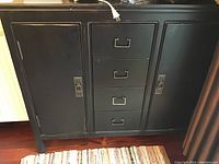 Front view of black wooden cabinet showing two doors and four drawers.