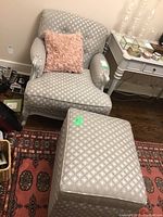 Grey diamond-patterned upholstered armchair and matching ottoman on rug