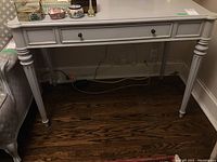 Front view of painted desk showing single center drawer and turned legs
