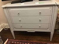 Front view of painted gray dresser showing three drawers and curved top edge