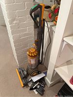 Upright vacuum with cord wrapped on side and attachments on floor