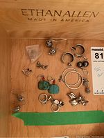 Overview of all ten pairs of earrings arranged in a wooden drawer
