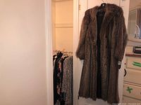 Full length raccoon fur coat hanging, showing overall length and cut.