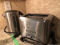 Breville toaster and electric kettle side by side on kitchen counter, showing overall condition and design