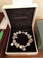 Pandora white presentation box open, showing bracelet and charms on black velvet insert