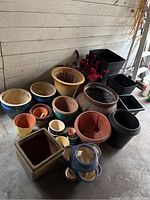 Front view of entire assortment of pots arranged on concrete floor against wall