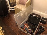 Clear plastic bin with assorted purses and wallets of various sizes and materials including leather and cloth