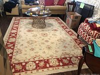 Overhead view of entire rug showing cream field with vine-and-flower design and red border