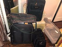 Four luggage items including two suitcases and two duffel bags arranged on floor and chair.