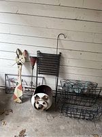 Wide photo showing metal pig planter, wooden cat yard art, metal bird & snake art, plant baskets, and metal torch.