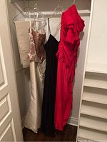 All three dresses hanging together: beige Ava Ti strapless dress with beaded bodice, black Laundry spaghetti strap dress, red Mignonette strapless dress with ruched detail and wrap.