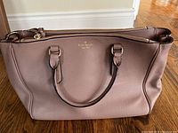 Front side of the Kate Spade handbag showing full shape, soft pebble texture, and dual handles.