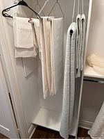 Closet area showing hanging linens including quilt and pillow shams on right, and tablecloths and napkins on left.