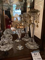 Photo of large and medium glass candle holders on shelf showing tall designs with gold rim and hanging bead chain decorations.