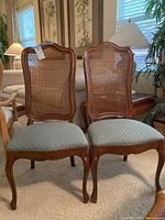 Pair of wooden dining chairs with cane backs and upholstered seats, front view