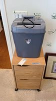 Overall view of a wooden two-drawer filing cabinet with two curved wooden handles on caster wheels, topped with a gray Intimus NT PS10cc shredder with control buttons and a paper slot on black top.