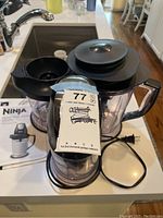 Front view of Ninja Master Prep Professional blender showing main motor unit, smaller blending jar, large pitcher jar with lid, power cord, original manual and packaging with tag sticker attached.
