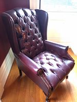 View of the armchair from front corner showing tufted seat and back, wood feet, and armrest details.