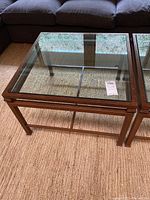 Clear glass top coffee table with medium brown wood frame, showing legs and frame detailing.