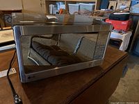 Front and side view of the LG microwave showing the reflective glass door and stainless steel finish, kitchen and garage background