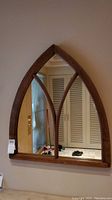 Full view of the wood framed mirror showing its Gothic arch shape and divided glass design.