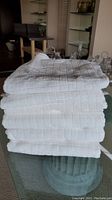 Stack of six white waffle weave towels with a visible textured checkered waffle pattern.
