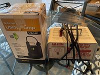 Photo of EcoFlo Utility Pump box next to AM-612M battery charger with cables coiled on top.