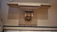 Front view of wall sconce shelf mounted on wall, showing symmetrical decorative corbels and shelf top.