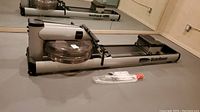 Side angled view of rowing machine showing water tank and rail