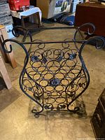 Full view of the black metal wine rack showing the grape cluster design and circular bottle holders.