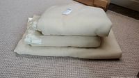 Stack of three cream/ivory wool blankets with smooth satin trim on a textured beige carpet.