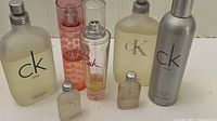 Full lot of Calvin Klein CK One and Pink cologne bottles shown on white surface.